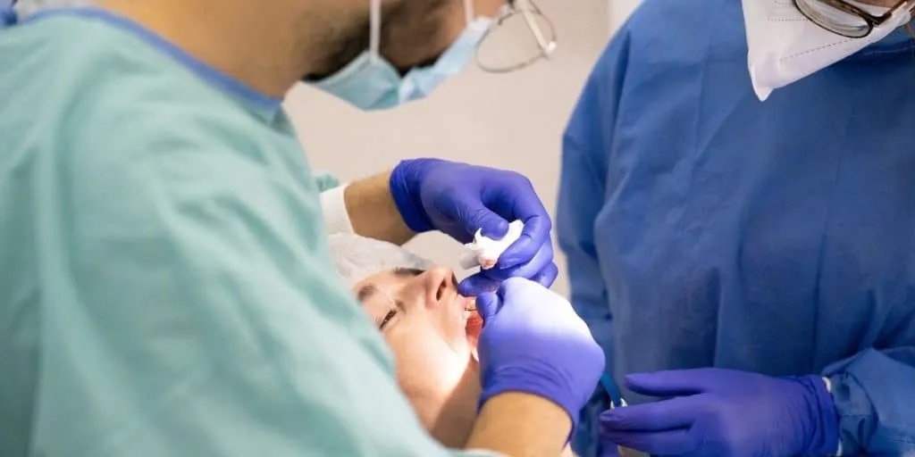 Two dental professionals doing treatment on a patient.