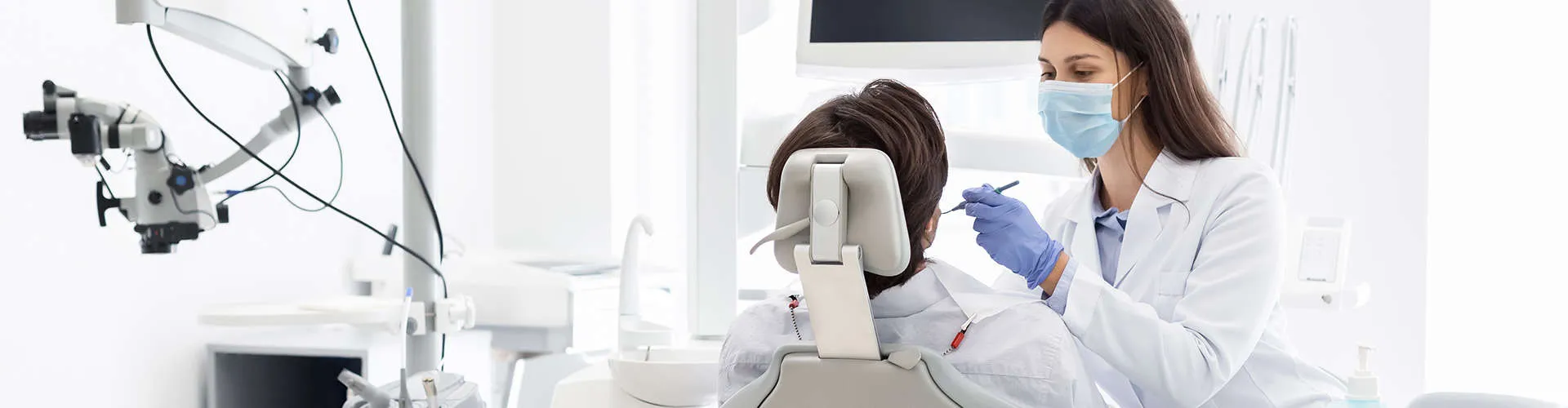 Female dental professional examining patient's mouth using a dental tool.