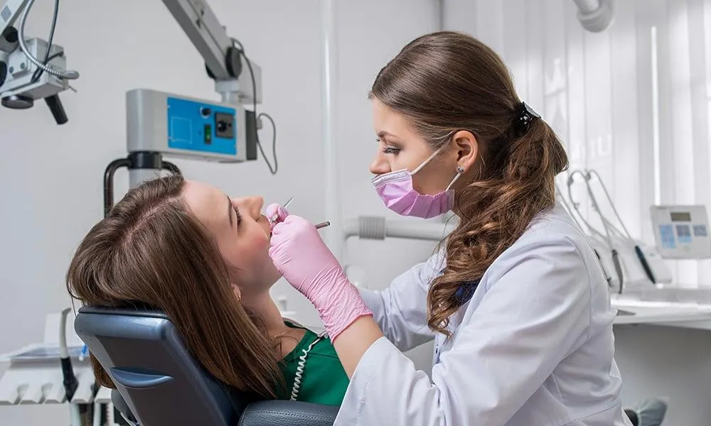 Female dentist doing scaling and root planing on female patient.